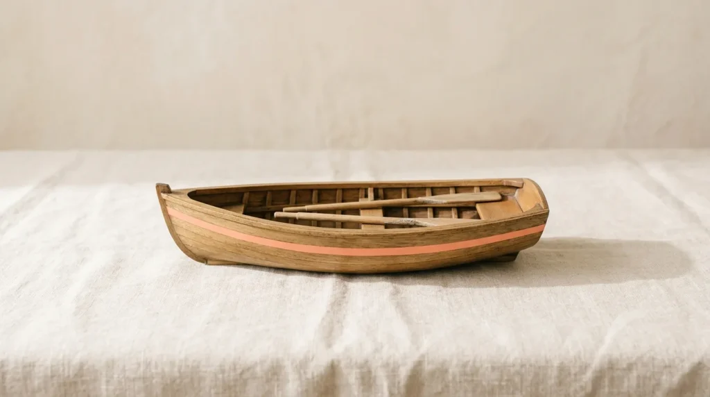 Small wooden rowboat model with two oars resting inside